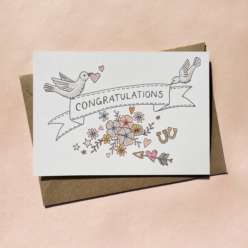 Greeting card with illustrated 'Congratulations' text and love/wedding themes decorative elements on an off-white background. Card blank inside.
